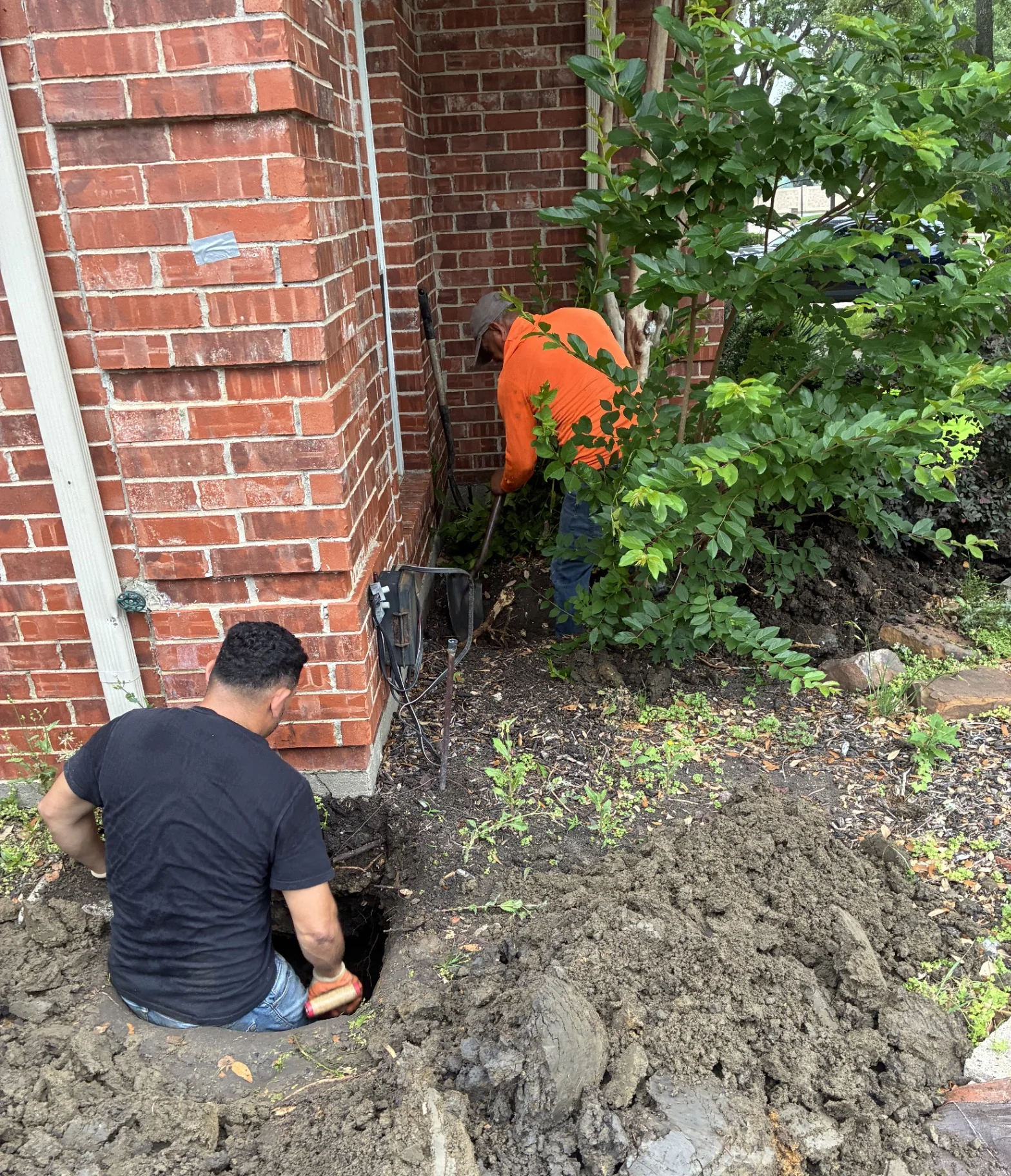Foundation repair crew working alongside a brick home in North Texas
